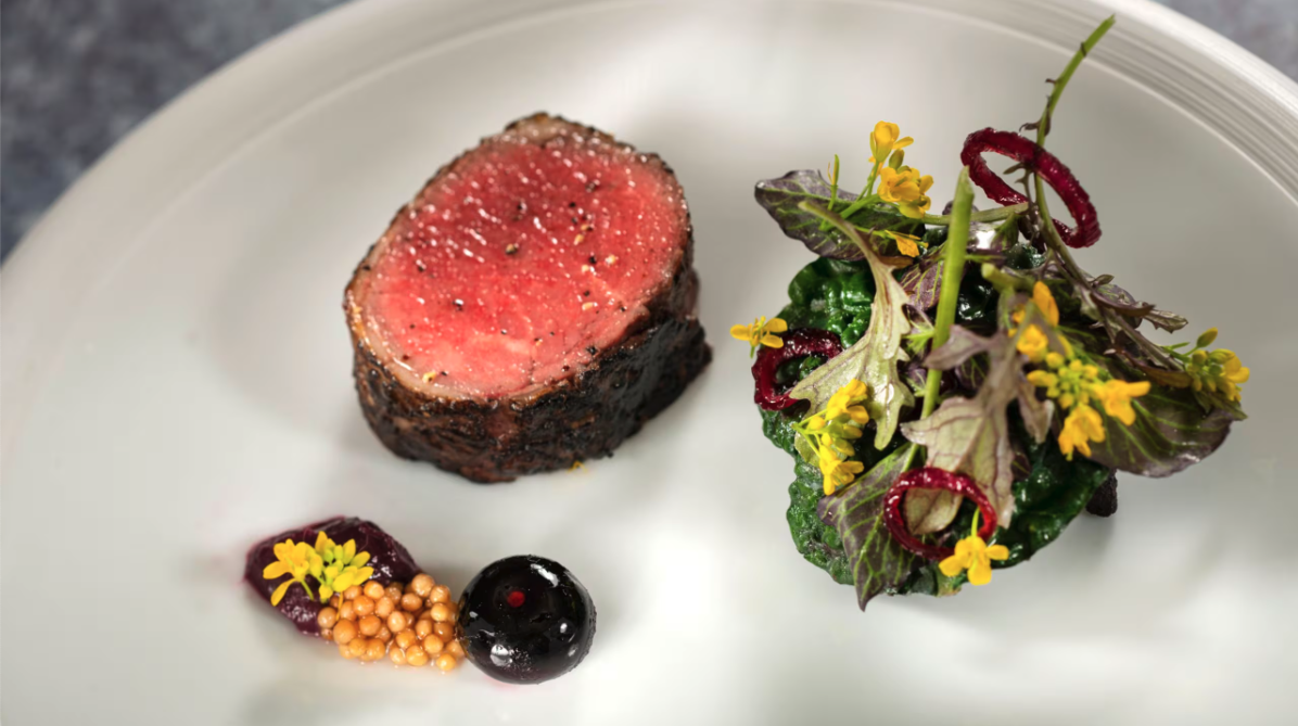 plate with slice of medium rare steak and small salad